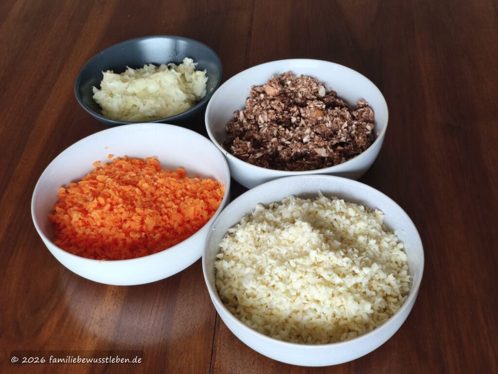 Vier Schüsseln mit kleingehackten Zutaten für eine Gemüsebolognese: Möhren, Champignons, Zwiebeln und Sellerie.