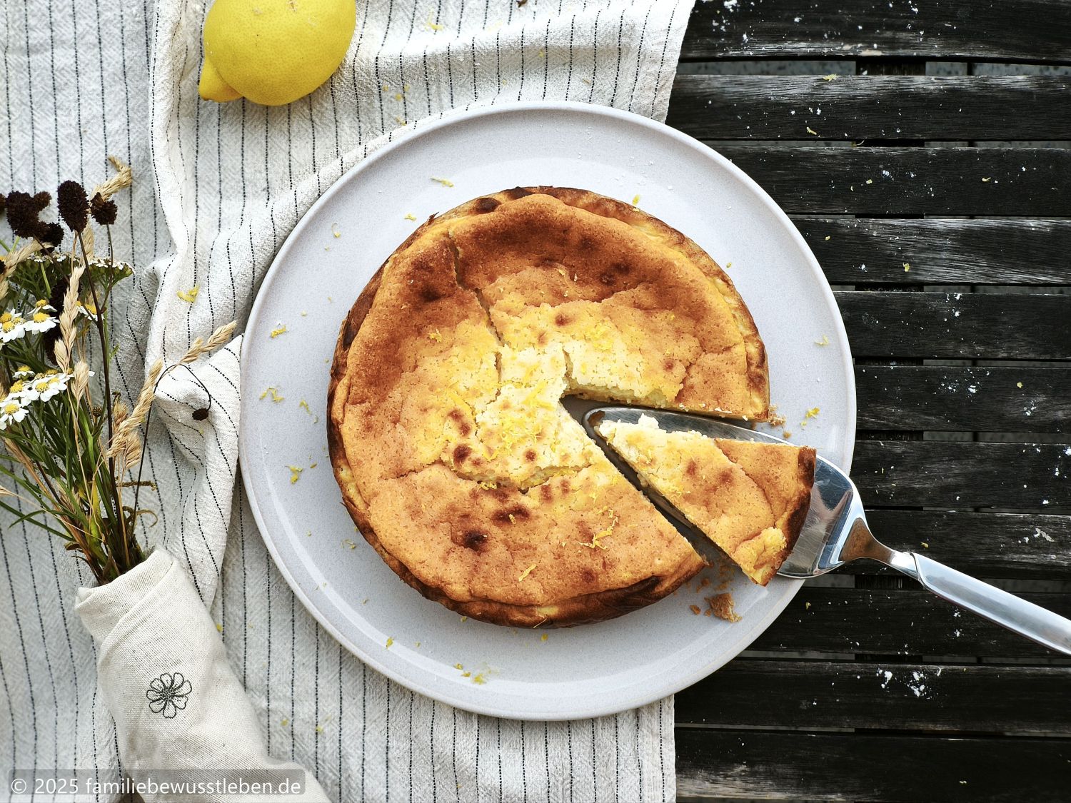 Ein gesunder Käsekuchen von oben fotografiert. Der Kuchen ist frisch angeschnitten und auf einem Kuchenheber liegt das erste Stück.