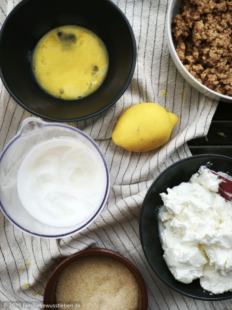Die Zutaten für den gesunden Käsekuche: Magerquark, Eiweiß und Eigelb getrennt, eine Zitrone und Zucker.